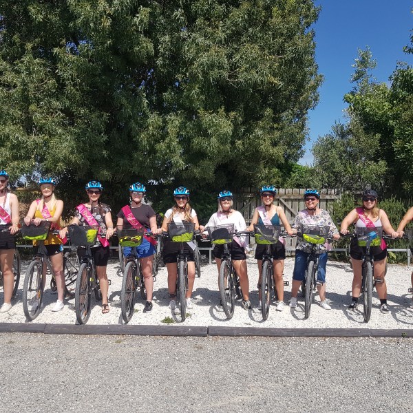 Group of people with bikes and blue helmets, standing outdoors on a sunny day.