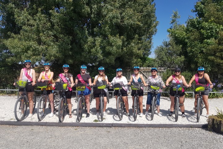 Group of people with bikes and blue helmets, standing outdoors on a sunny day.