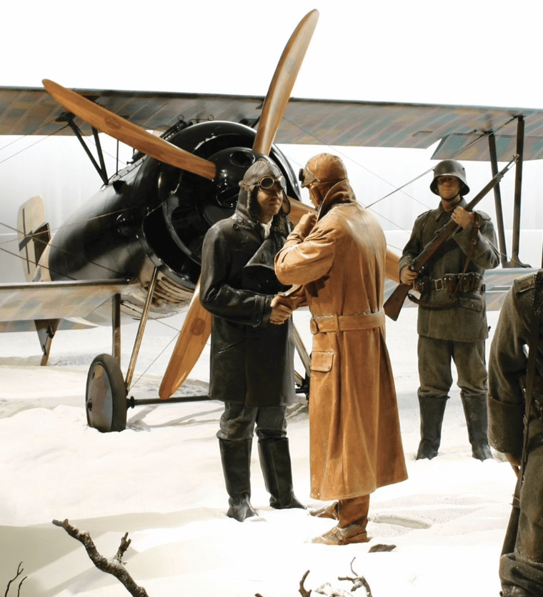 WWI soldiers and aviators in winter attire near a biplane display.