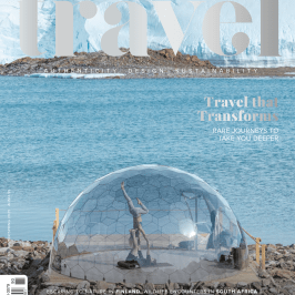 Luxury Travel magazine cover with a glass dome on a rocky shore by the sea.