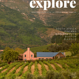 House amidst vineyard with mountain backdrop, text reads 'explore.'