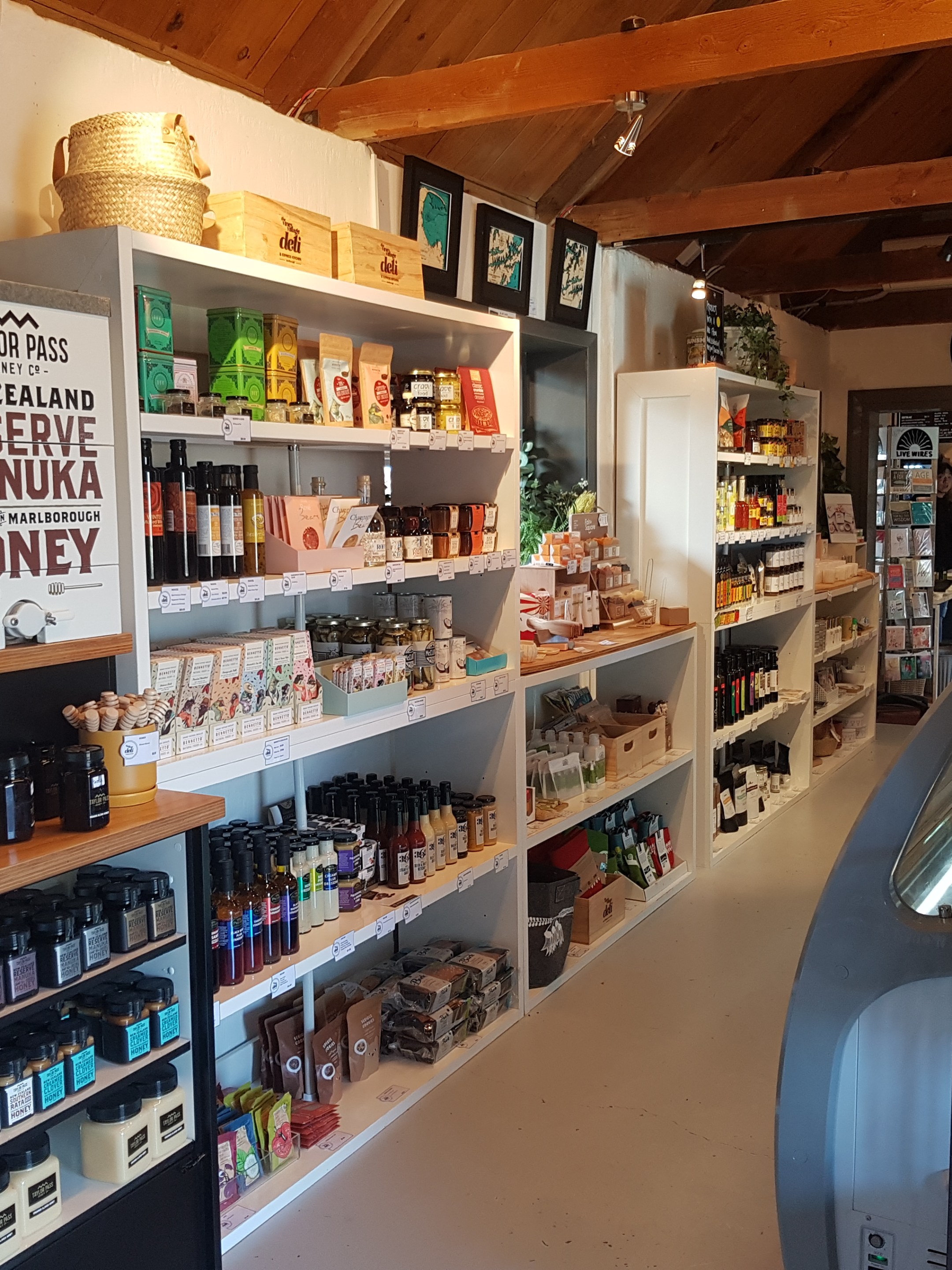 Store interior with shelves displaying honey products and other goods. Wooden ceiling and cozy atmosphere.