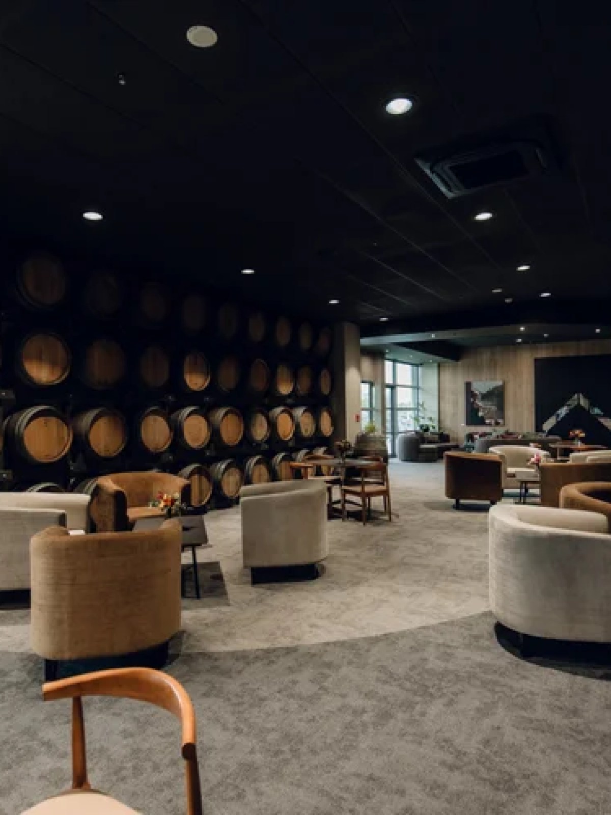 Cozy lounge with barrel wall, plush chairs, and ambient lighting.