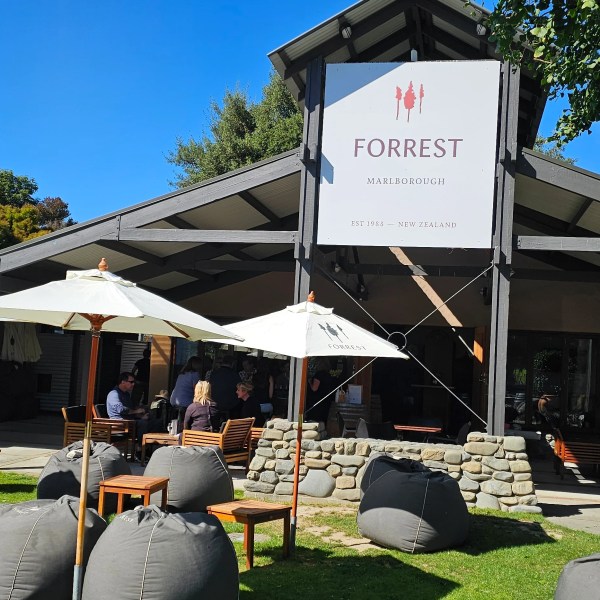 Outdoor seating area with umbrellas, bean bags, and people under a large sign reading 'Forrest Marlborough'.