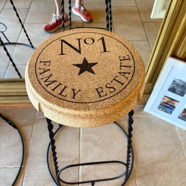 Stool with cork top labeled 'No1 Family Estate' on tile floor.
