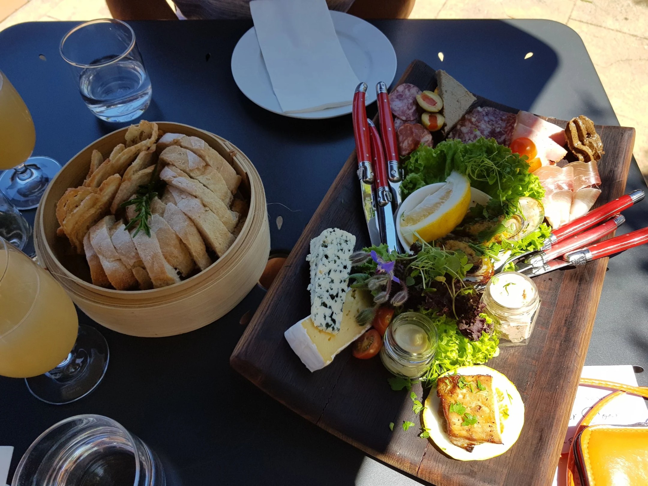 Charcuterie board with meat, cheese, bread, and drinks on a table.