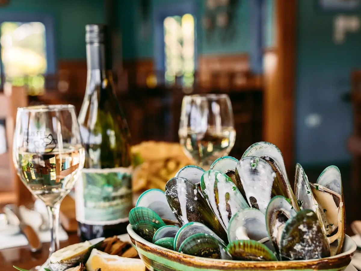 Plate of mussels with wine glasses and bottle from the mussel pot